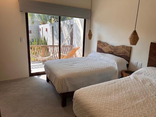 two beds in a room with a balcony at Hotel Almendros Bonfil in Acapulco