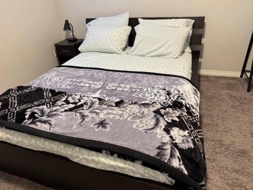 a bed with a black and white comforter and pillows at Quiet Comfortable 1-Bedroom in Calgary