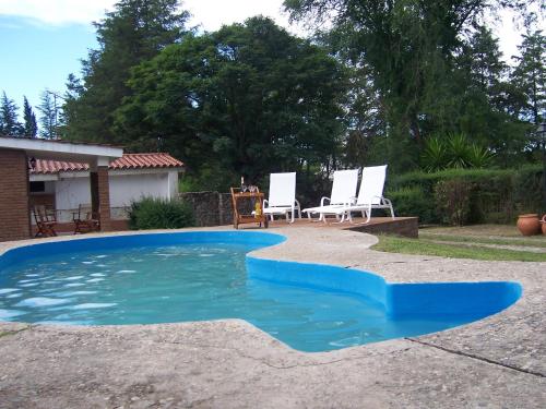una piscina azul con 2 sillas en un patio en El Descanso en 