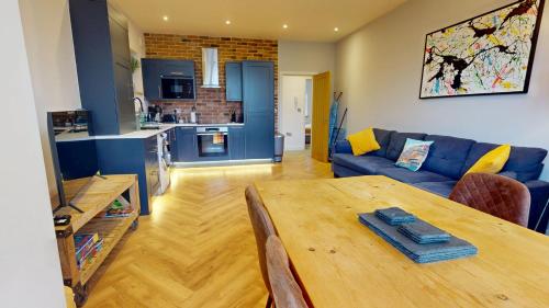 a living room with a wooden table and a blue couch at Stylish 2 Bed Apt, 2 Minute Walk From The Beach. in Sheringham