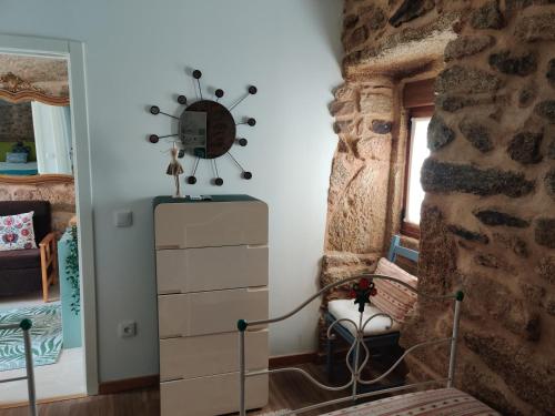 a bedroom with a stone wall and a dresser at Casa do Sobrado-Gralhas-Montalegre in Gralhas