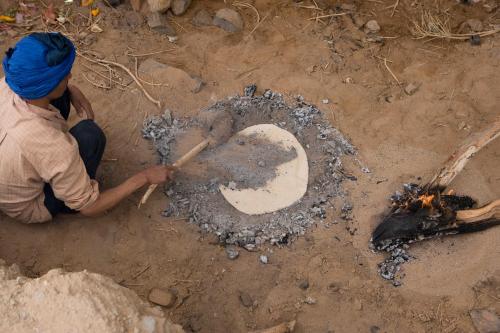 a woman is making a stone in the dirt at Tifawin Home And Garden in Mirleft