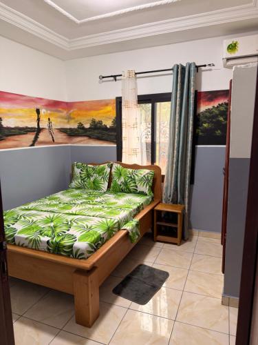 ein Schlafzimmer mit einem Bett und einem Gemälde an der Wand in der Unterkunft Résidence Yavanie in Kribi