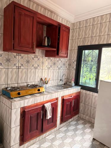 eine Küche mit roten Holzschränken und einem Fenster in der Unterkunft Résidence Yavanie in Kribi