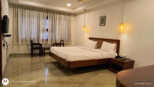 a hotel room with a bed and a table at Hotel Raya's Annexe 1 in Kumbakonam