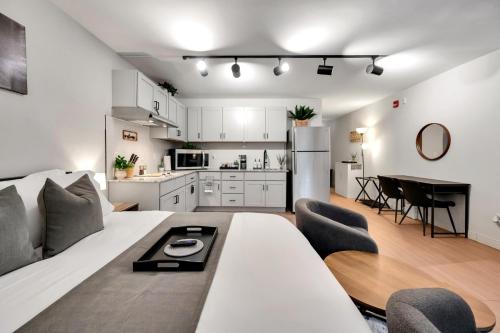 a living room with a white couch and a kitchen at Upscale Midtown Studio and Private Balcony in Raleigh