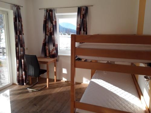 a bedroom with a bunk bed and a desk and a window at Apartments Steger in Faak am See