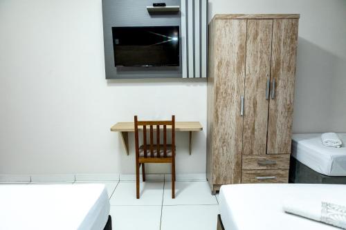 a room with a desk and a chair and a cabinet at Hotel Rota 090 in Piraí do Sul
