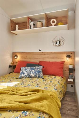 a bedroom with a bed with a yellow blanket and red pillows at Camping La Siesta - Maeva in L'Aiguillon-la-Presqu'île