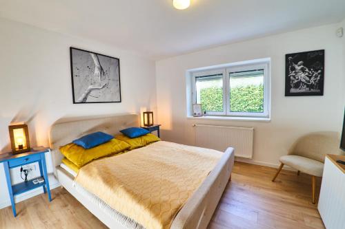 a bedroom with a bed and a chair and a window at Volt Egyszer Egy Apartman Pécs in Pécs