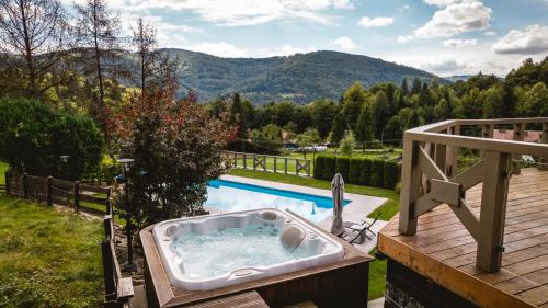 a bath tub sitting on a deck next to a pool at Dom Beskidy in Brenna