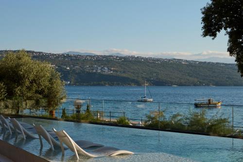 a swimming pool with chairs and a body of water at Amadria Park Grand Hotel 4 Opatijska Cvijeta in Opatija