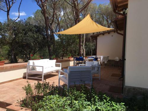 a patio with white chairs and a yellow tent at Tenuta le marze in Castiglione della Pescaia