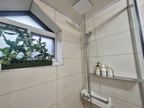 a shower with a window and two bottles on a shelf at Maison Stay in Samgong