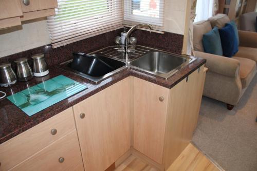 a kitchen with a sink and a couch at Golden sands ingoldmells plot 337 in Skegness