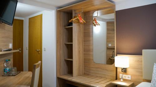 a room with a bed and a closet with a mirror at Hotel Maximilian in Zeitz