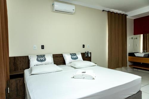 a bedroom with a large white bed in a room at Hotel Rota 090 in Piraí do Sul