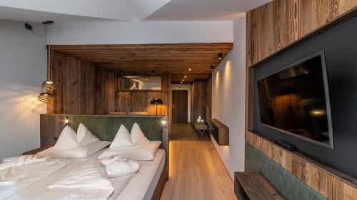 a bedroom with a bed with white pillows and a television at Hotel Villa Monica in Dobbiaco