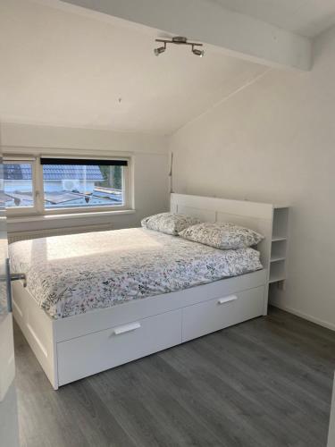 a white bedroom with a bed and a window at De Keizersmantel in Son