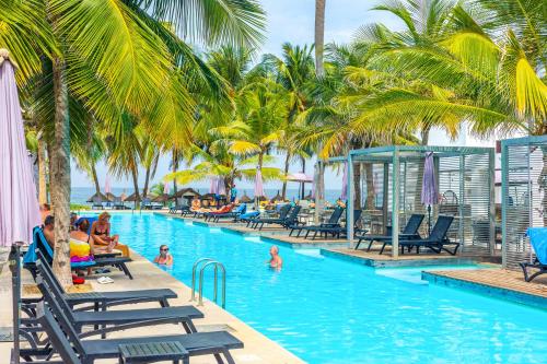 a pool at a resort with palm trees and people in it at Kalimba Beach Resort in Kotu