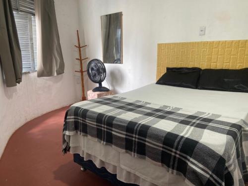 a bedroom with a bed with a black and white checkered blanket at Pousada Cisne Branco in Natal