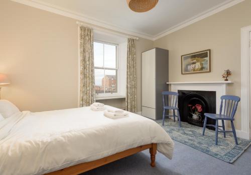 a bedroom with a bed and two chairs and a fireplace at Sandy Neuk in North Berwick