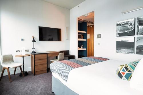 a bedroom with a bed and a desk and a tv at Sandman Signature Newcastle Hotel in Newcastle upon Tyne