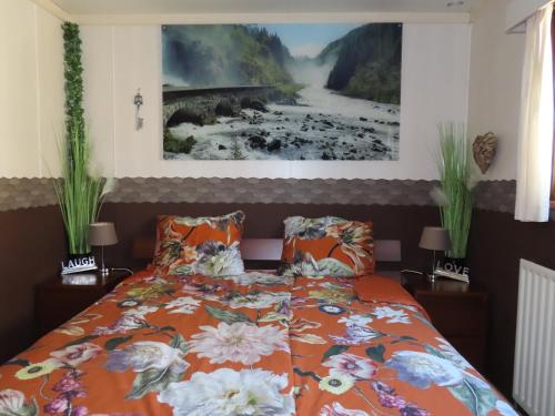 a bedroom with a bed with an orange comforter at Veluwe Park Reewold Chalet Infinity in Putten