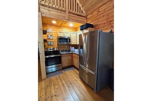 a kitchen with a stainless steel refrigerator and wooden cabinets at Charlie Long Cabin - Active Heroes in Shepherdsville
