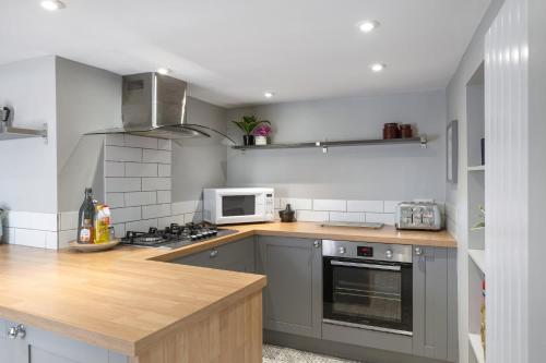 a kitchen with a stove and a microwave at Modern Cottage in Central Exeter in Dean