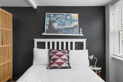 a bedroom with a bed and a painting on the wall at Modern Cottage in Central Exeter in Dean
