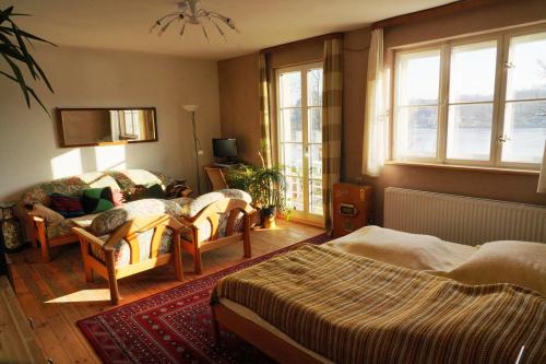 a bedroom with two beds and a couch and windows at Pension Pichelsdorf in Berlin