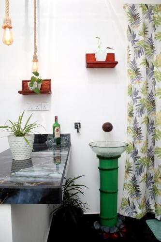 a bathroom with a green sink and a glass table at Riverside Bliss Cottage in Demodera