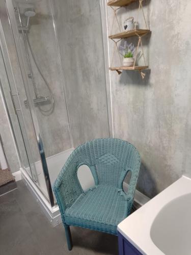 a bathroom with a green chair next to a shower at Pankhurst, Louth in Louth