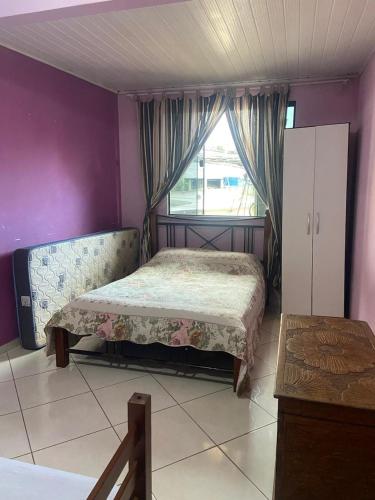 a small bedroom with a bed and a window at Casa temporada in Arraial do Cabo