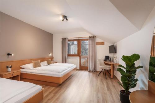 a bedroom with two beds and a desk and a window at MyLiving - Hotel B&B by Majestic Resorts Dolomites in San Lorenzo di Sebato