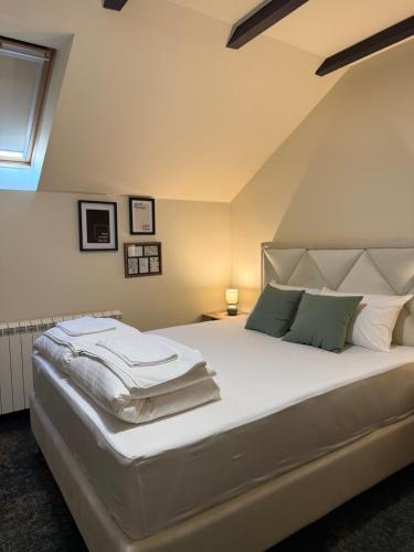 a bedroom with a large white bed with green pillows at Amfora Novi Sad in Pasuljište