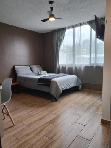 a bedroom with a bed and a large window at Compact Studio Apartment Casa Icacos #8 in Mexico City