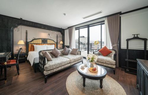a hotel room with a bed and a couch and a table at Luxe Paradise Suites Hotel & Spa in Hanoi