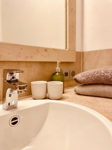 a bathroom sink with two cups on top of it at Brandmayerhof in Oberding