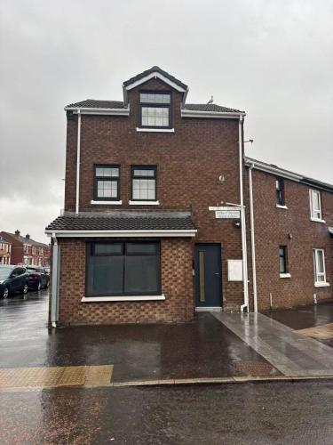 a brick building with windows on a wet street at Stay in City Centre 1 in Belfast