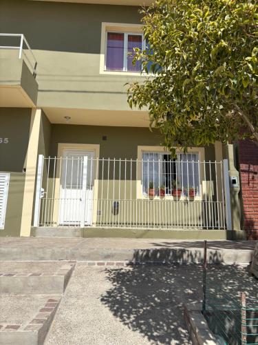 a house with a white fence in front of it at Suarez home in Puerto Madryn