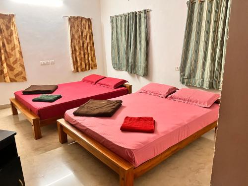 two beds in a room with red sheets at Jamath Villas 1307 in Kīlakarai