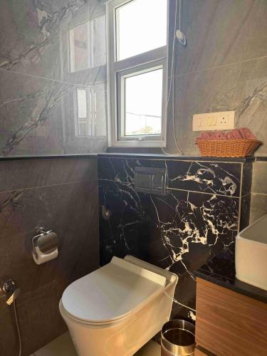 a bathroom with a white toilet and a window at Pacation Home Stay in Noida