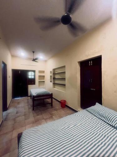 a bedroom with two beds and a ceiling fan at SMK cottage in Rāmeswaram