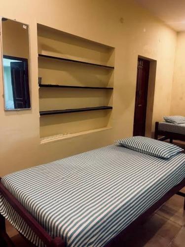 a bed in a room with a wall with shelves at SMK cottage in Rāmeswaram