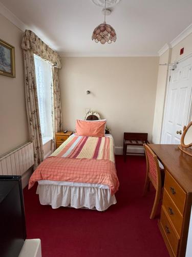 a bedroom with a bed with pink and orange sheets at Havelock Guesthouse in Saint Helier Jersey