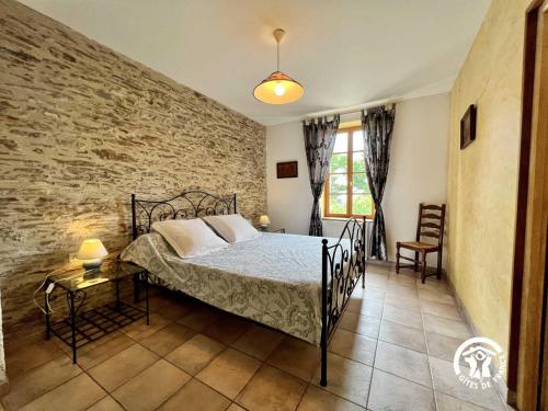 a bedroom with a bed and a brick wall at Domaine de la calm in Villardonnel