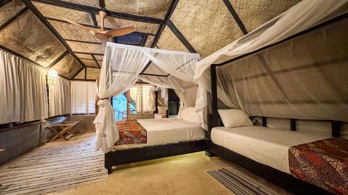 a bedroom with two beds and a ceiling fan at Lions Eco Resort & Spa in Malindi