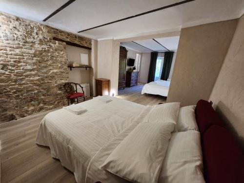 a bedroom with a large bed and a stone wall at Monforte Country House in Monforte dʼAlba